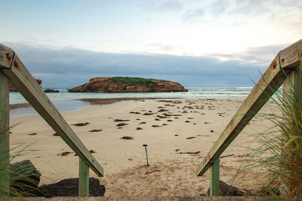"Scenic view captured by Jordan Gagne of steps leading down to a sandy beach, with picturesque coastal scenery in the background."