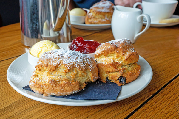 Plate of scones with jam and clotted cream on a wooden table