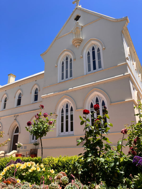 View of the front for the Convent at Koroit on a blue sky day with red roses.