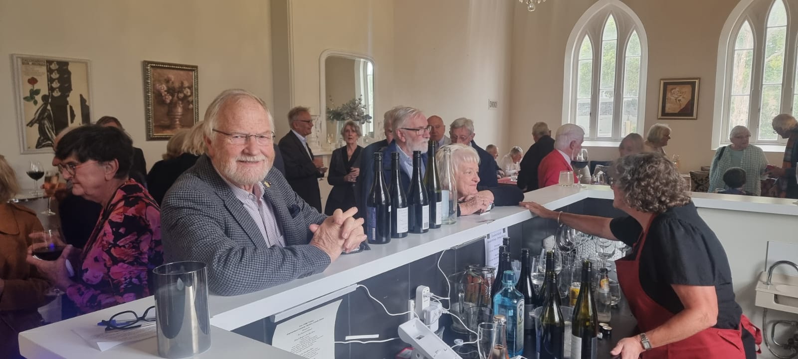A view looking out from the bar at The Convent at Koroit. The room is full of people. You can see arched windows.
