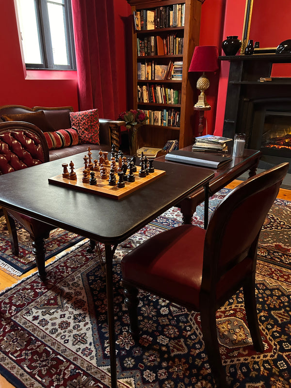 Room interior with a table, chairs, and books on shelves.