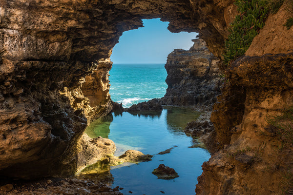 Dramatic rock formations along the great ocean road with views through to the ocean and a reflective pool of water.