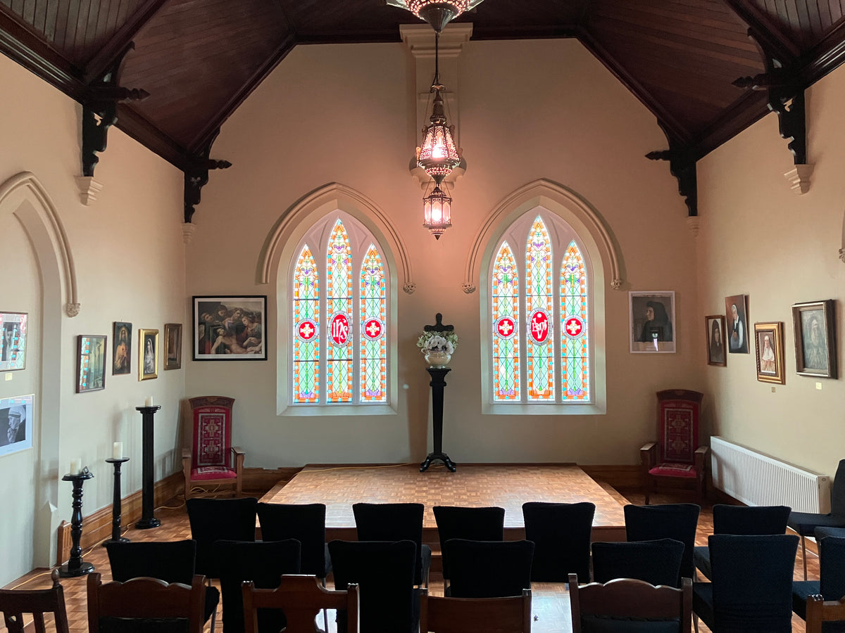 The Chapel at The Convent at Koroit with two stain glass windows and chairs in rows.